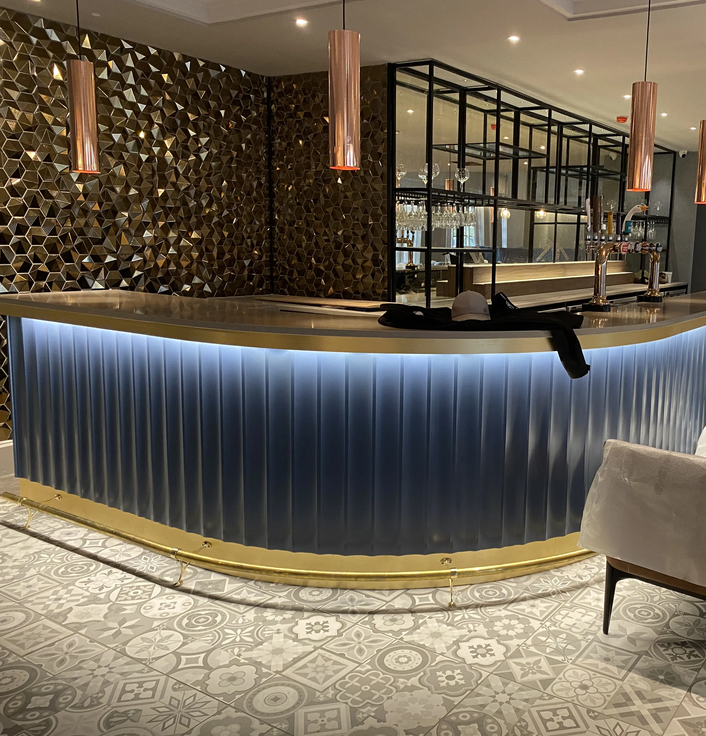 Curved navy fluted bar front with brass trim and a dark timber top
