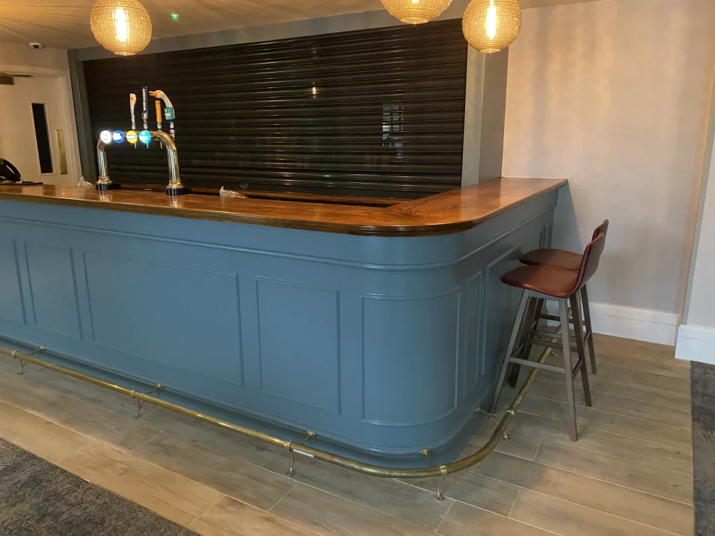Pale blue panelled bar with a timber top and brass foot rail