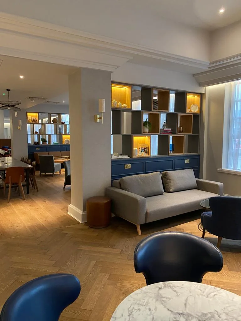 Lounge seating in front of lit display shelving with navy cupboards below