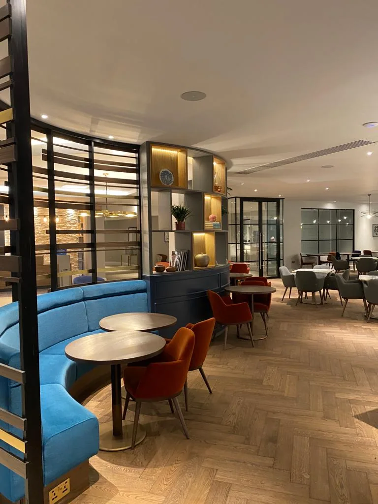 Curved blue banquette behind a black metal and timber screen