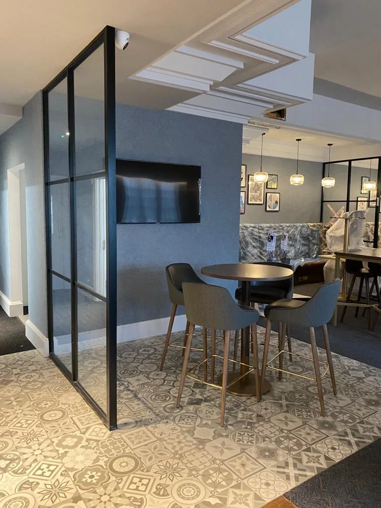 High tables inside a black-framed glazed screen