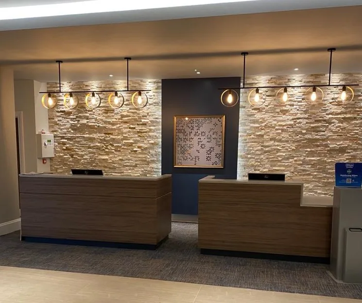 Timber hotel reception desks in front of a stone feature wall