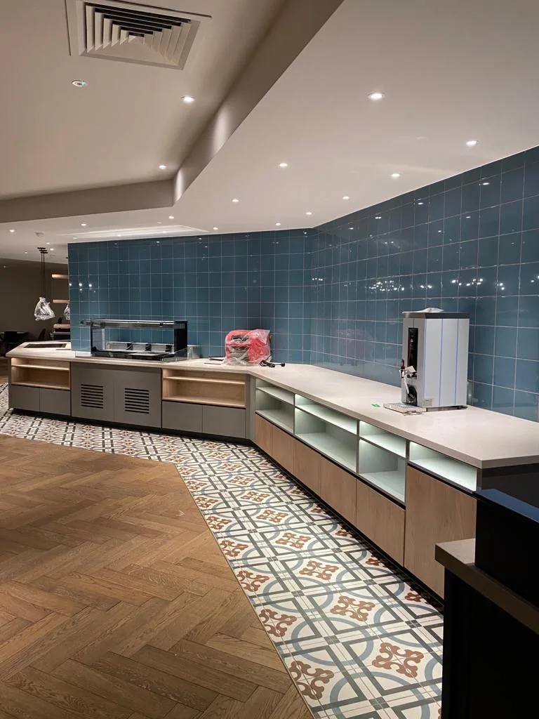Breakfast servery counters with white tops under a blue tiled wall