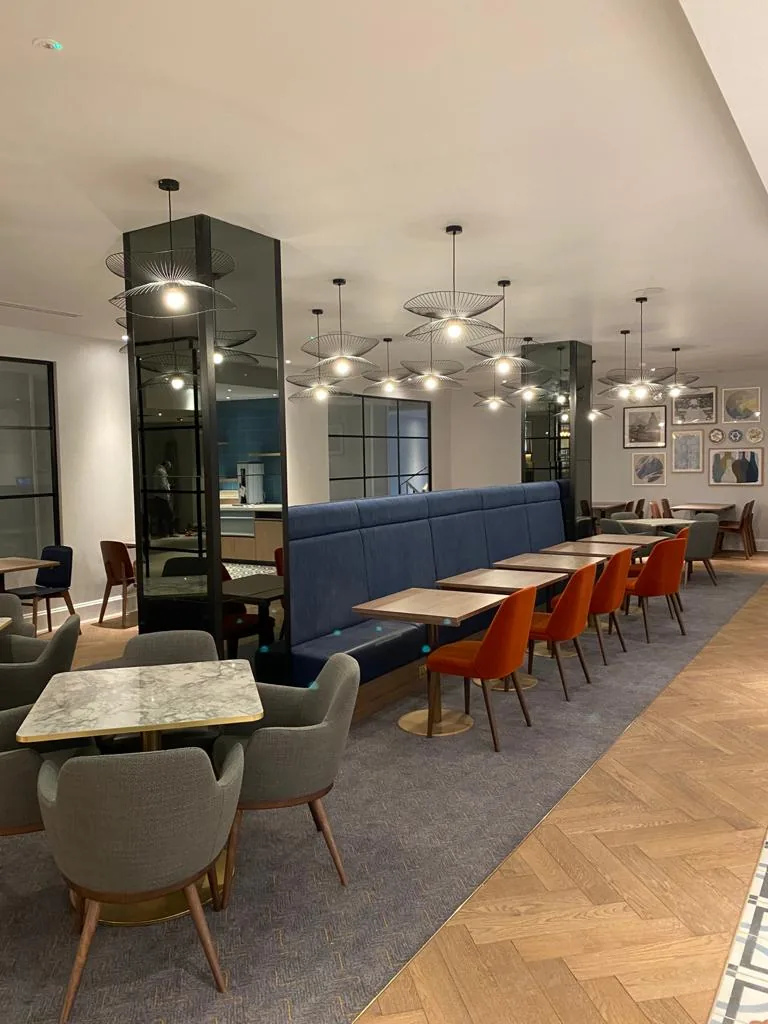 Hotel restaurant with a long navy banquette and rows of tables