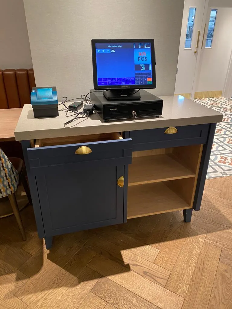 Navy painted till station with brass cup handles and an open shelf