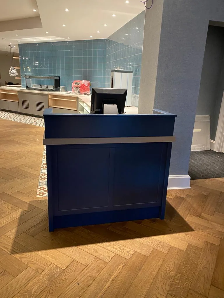 Navy front-of-house desk on a herringbone timber floor