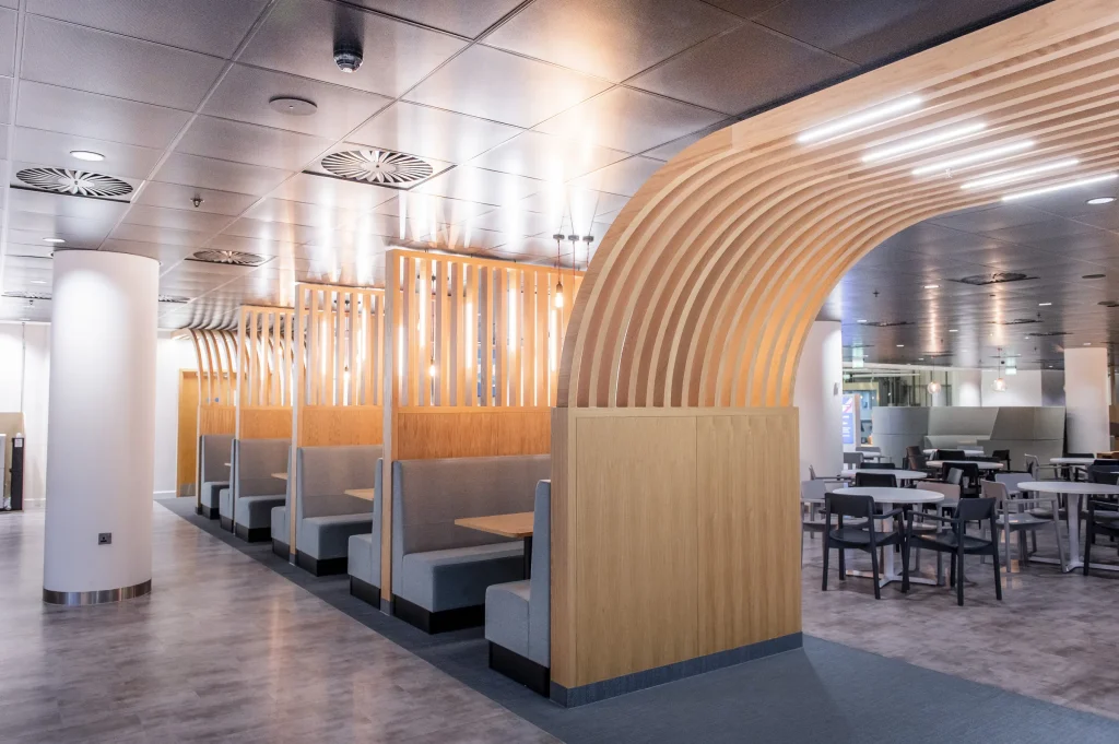 Booth seating framed by a curved slatted oak arch in a staff restaurant