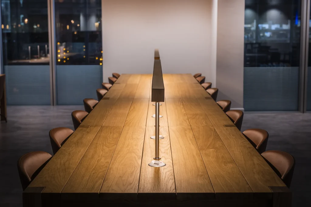 Long oak boardroom table with a central cable spine