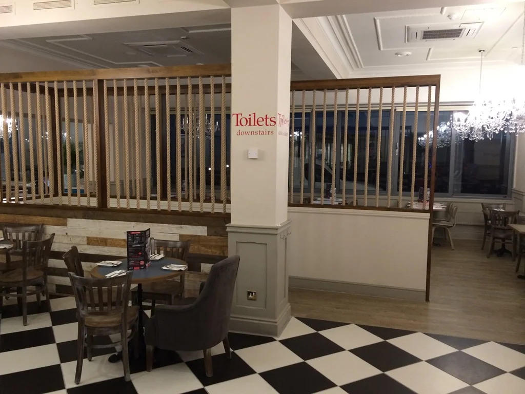 Rope-and-timber screens dividing dining areas above a black and white chequered floor at Harry Ramsden’s Blackpool