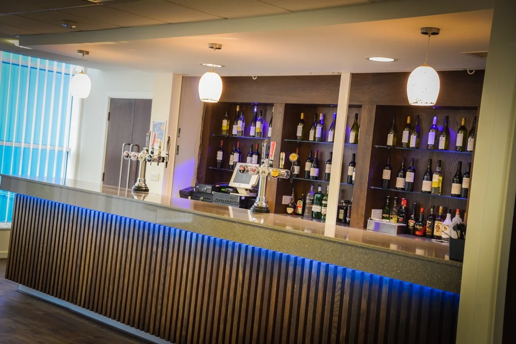 Leicester City F.C. bar with slatted timber front, blue LED under-lighting and timber-framed bottle shelving