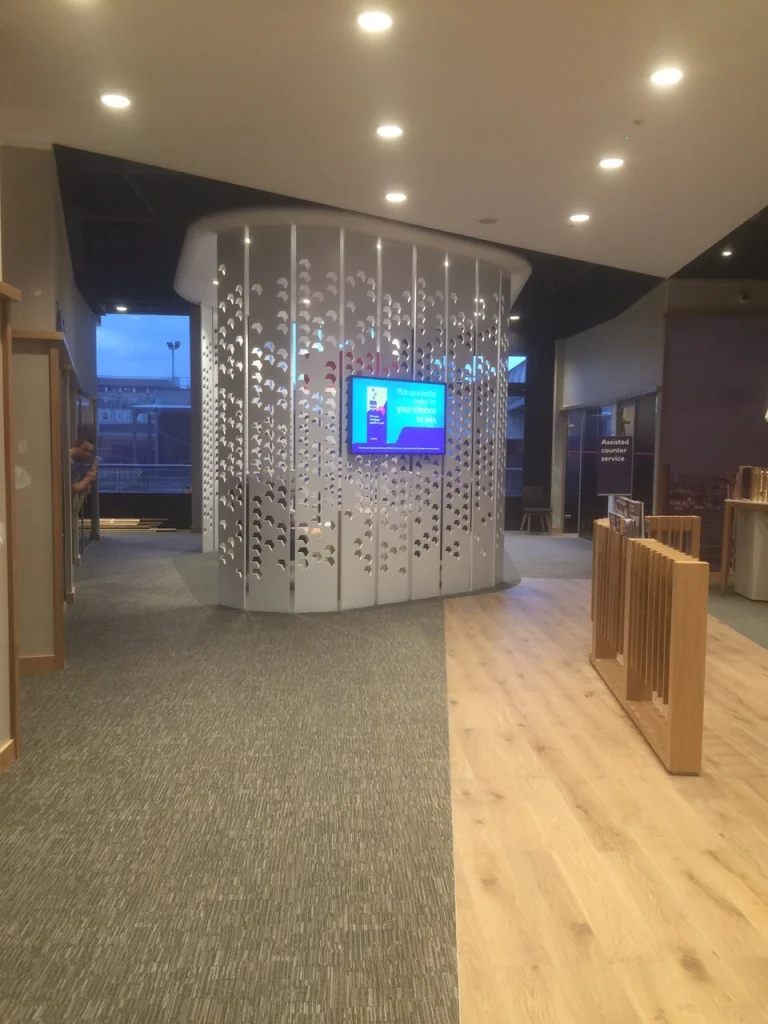 Curved white laser-cut screen around a meeting pod, with oak flooring, at NatWest Crossrail Canary Wharf