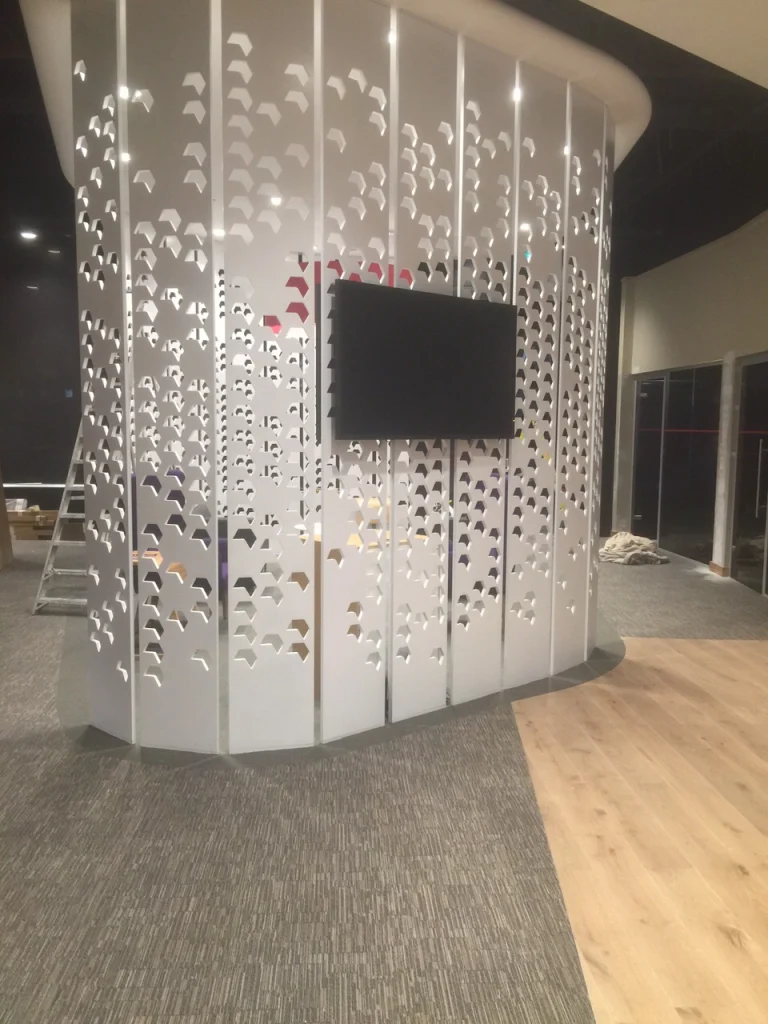 Perforated white panel screen with wall-mounted TV during fit-out at NatWest Crossrail Canary Wharf
