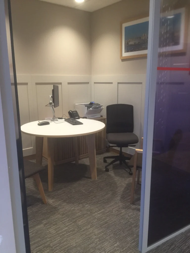 Private meeting room with white panelled walls, round table and desk at NatWest Crossrail Canary Wharf