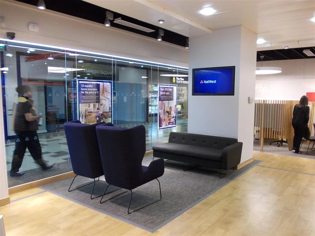 NatWest Telford branch waiting area with navy wingback chairs, sofa and glazed shopping centre frontage