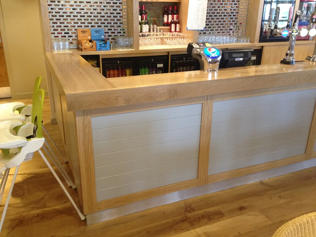 Close-up of solid oak bar top and panelled bar front with beer pumps at Park Resorts