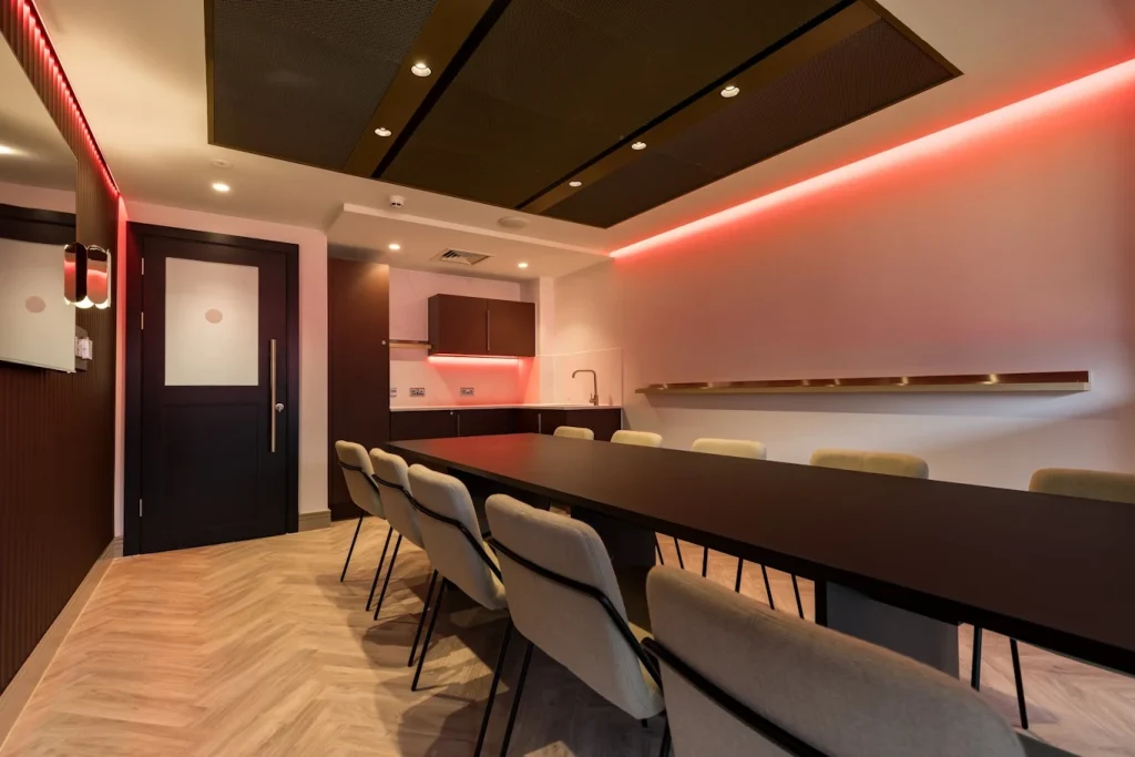 Long dining table, herringbone floor and brass picture shelf in a Premier League club hospitality room