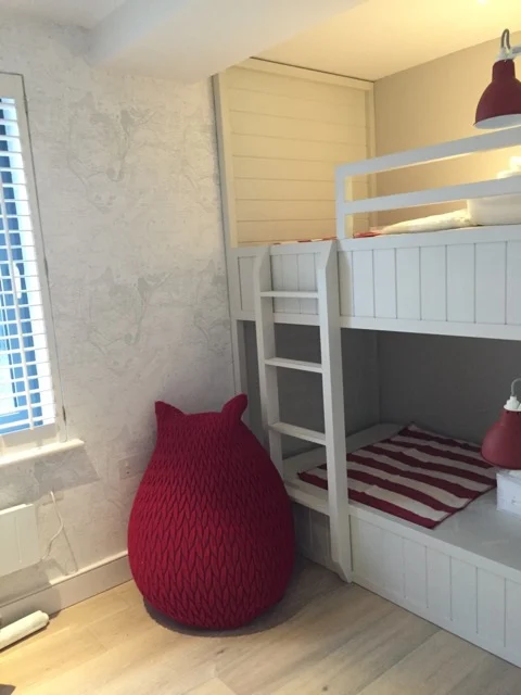 Premier Marinas bunk room with painted bunk beds, red knitted bean bag and map-print wallpaper