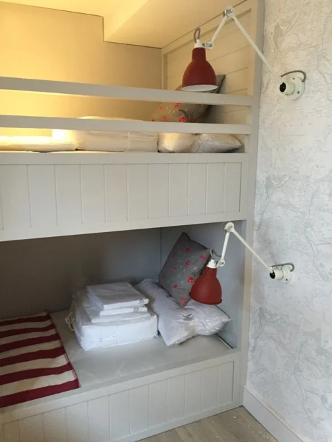 Upper and lower bunks with folded linen and red adjustable reading lamps in a Premier Marinas bedroom