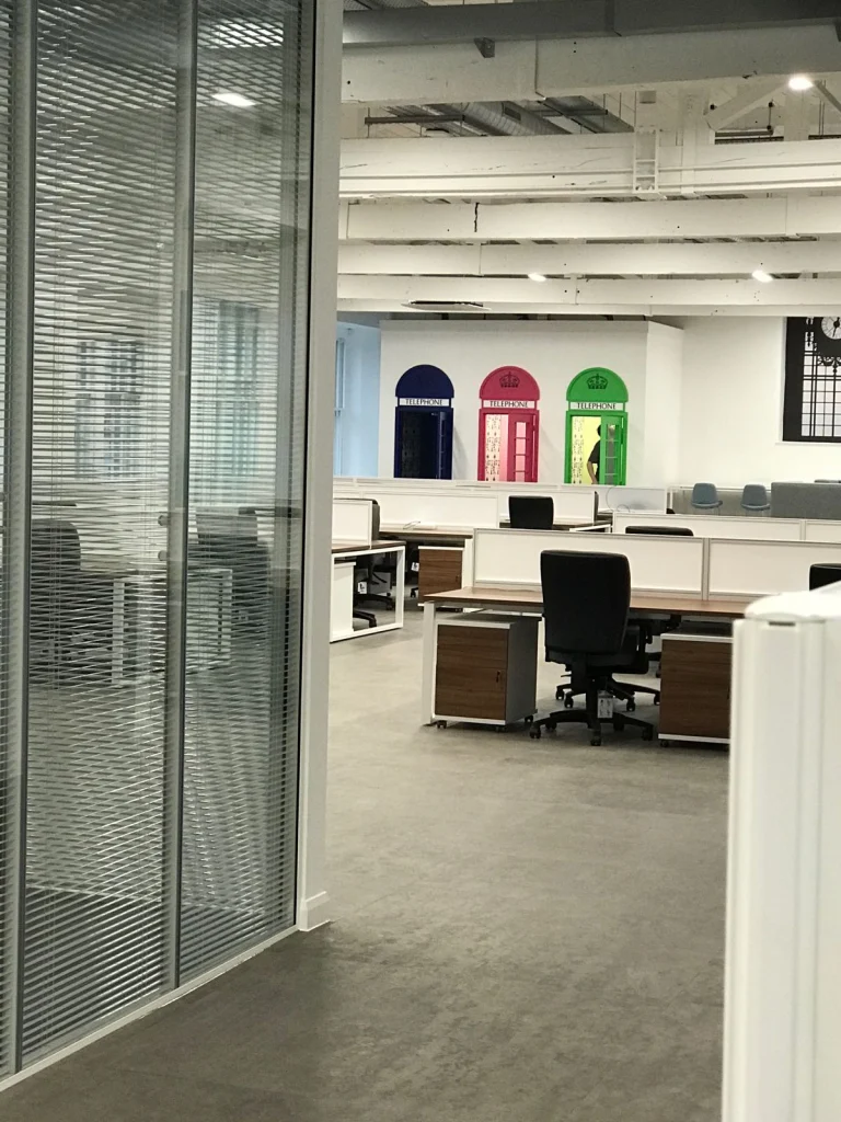 Open-plan office with walnut desks and telephone box door graphics at Vets4Pets Swindon