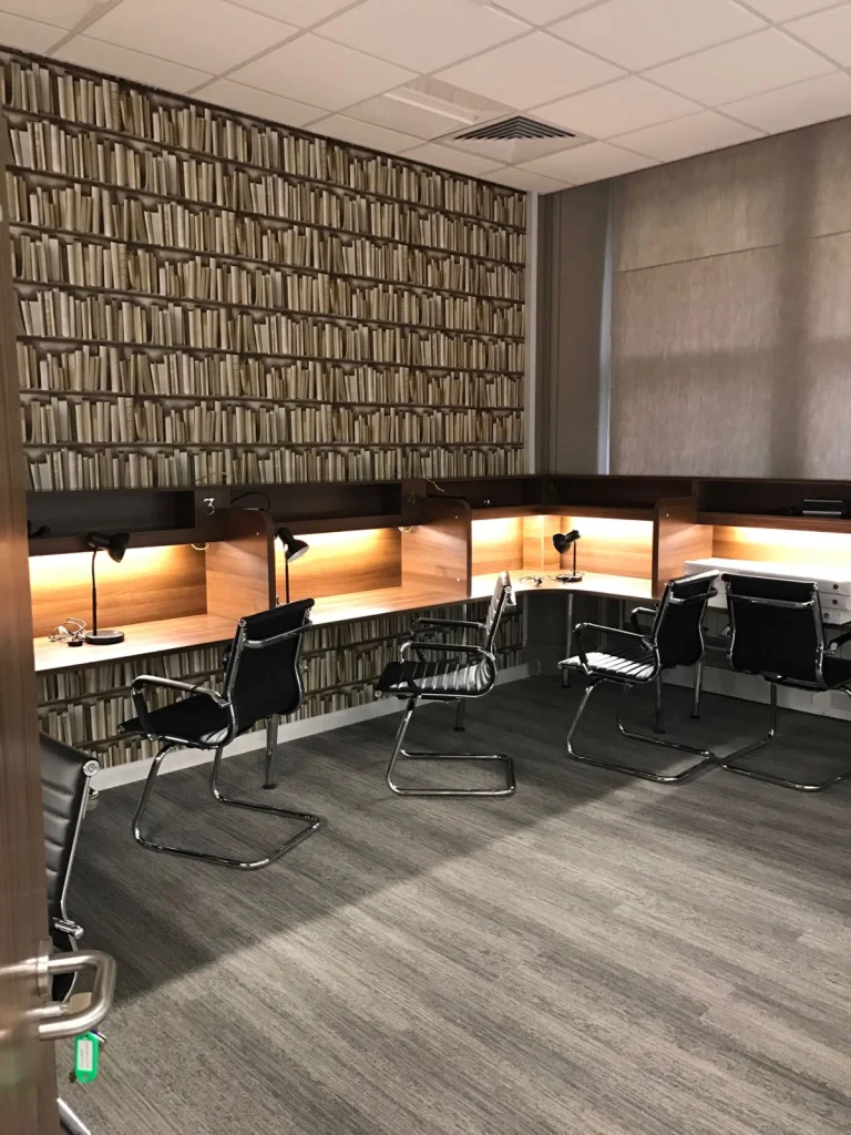 Study room with lit timber desk booths and bookshelf-print wallpaper at Vets4Pets Swindon