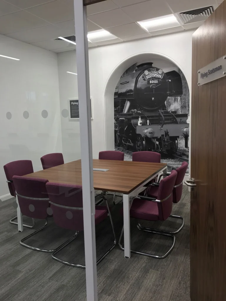 Flying Scotsman themed meeting room with walnut table and plum chairs at Vets4Pets Swindon