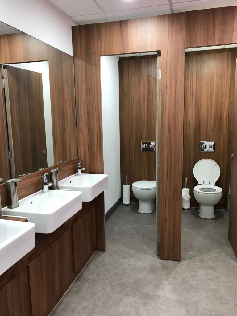 Washroom with walnut-effect cubicles, vanity unit and twin basins at Vets4Pets Swindon
