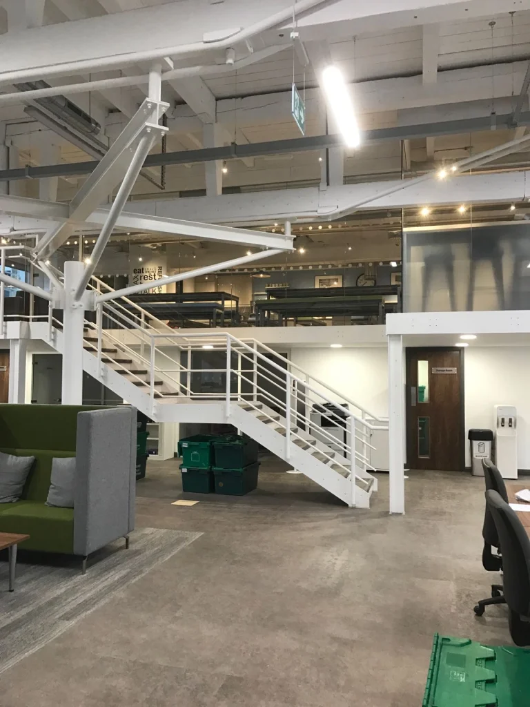 White steel staircase up to a glazed mezzanine in the open-plan office at Vets4Pets Swindon
